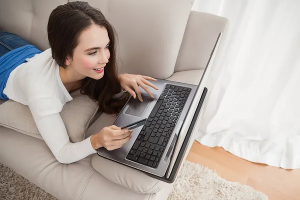 Pretty brunette shopping online on couch — Stock Photo, Image