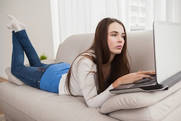 Pretty brunette using laptop on the couch — Stock Photo, Image