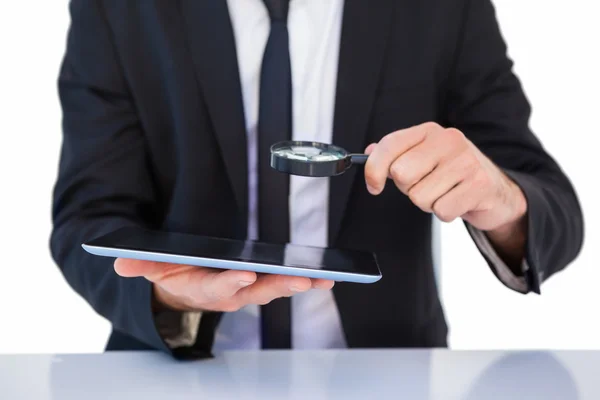 Empresario mirando su tableta a través de lupa — Foto de Stock