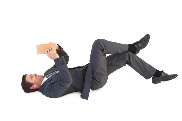 Businessman lying on the floor reading a book — Stock Photo, Image