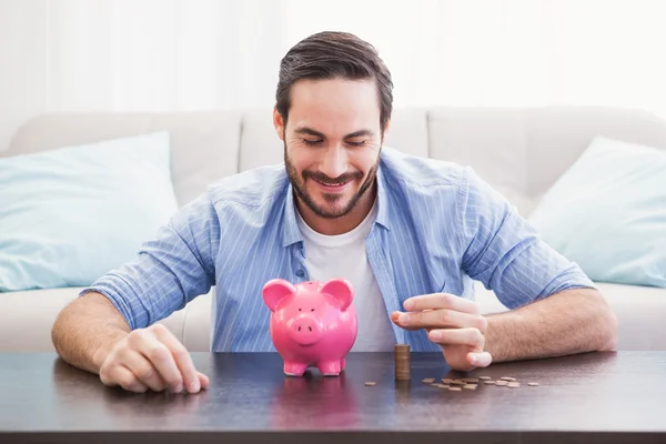 Lachende zakenman munten ingebruikneming piggy bank — Stockfoto