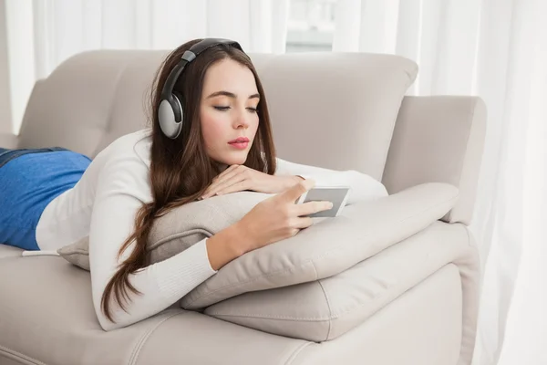 Bonita morena escuchando música en el sofá —  Fotos de Stock