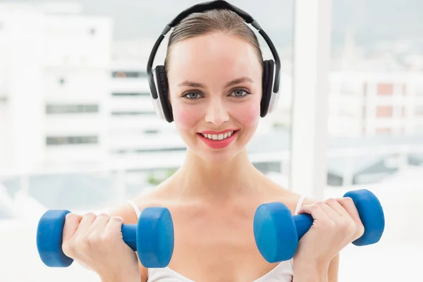 Fit brunette holding blue dumbbells — Stock Photo, Image