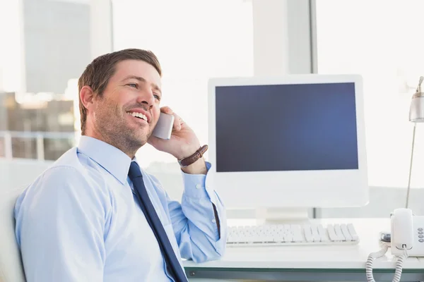 Un hombre de negocios sonriente llamando a su escritorio — Foto de Stock