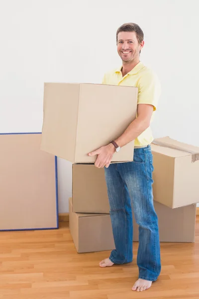 Smiling man carrying cardboard moving boxes at home — Stock Photo, Image