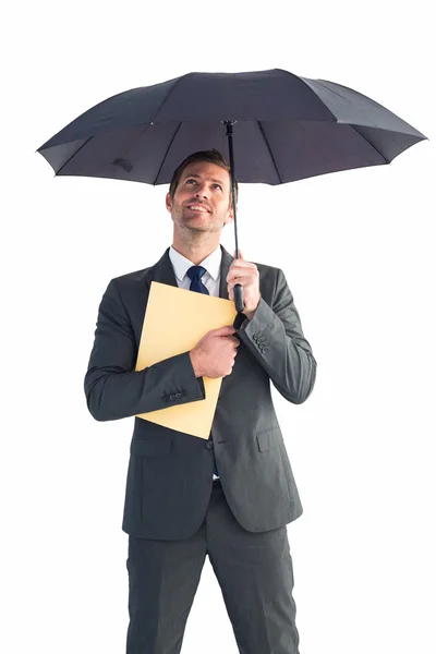 Businessman sheltering under umbrella holding file — Stock Photo, Image