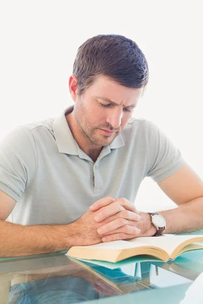 Casual businessman sitting at desk reading a book — Stock Photo, Image