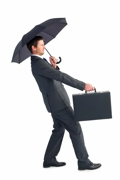 Businessman sheltering under black umbrella — Stock Photo, Image