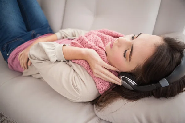 Mooie brunette luisteren naar muziek op de Bank — Stockfoto