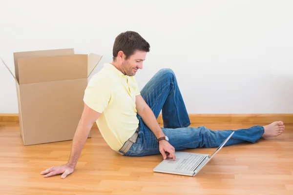 Casual man sitting on floor using laptop at home — Stock Photo, Image
