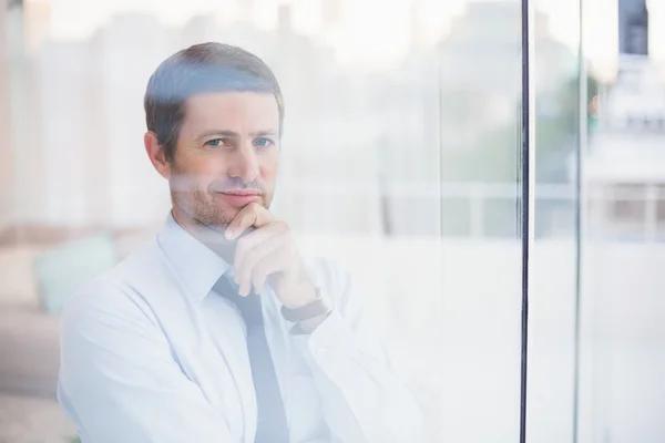 Un hombre de negocios sonriente mirando por la ventana —  Fotos de Stock