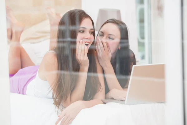 Pretty friends using laptop on bed — Stock Photo, Image
