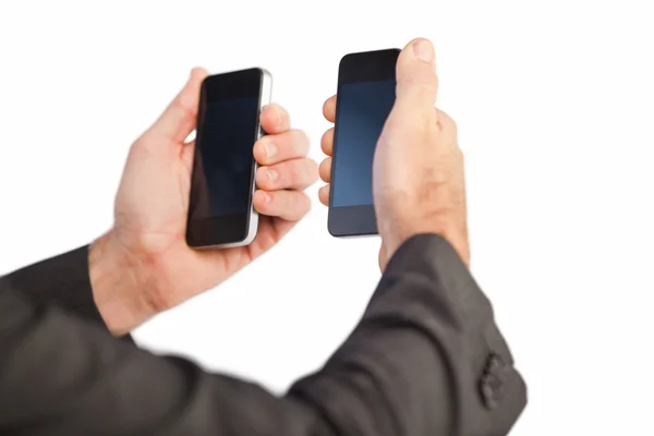 Businessman holding a phone in each hand — Stock Photo, Image