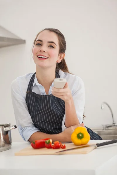 Pretty brunette cooking and watching tv — Stock Photo, Image