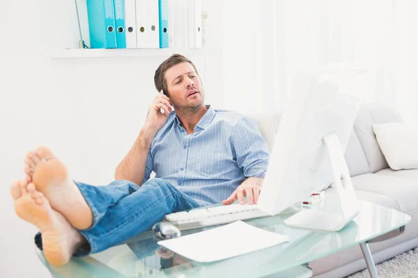 Empresario en el teléfono usando su computadora con los pies en alto —  Fotos de Stock