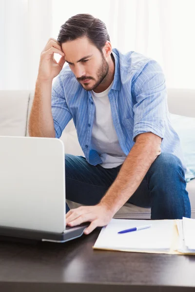 Orolig man sitter vid bord med laptop för att betala sina räkningar — Stockfoto