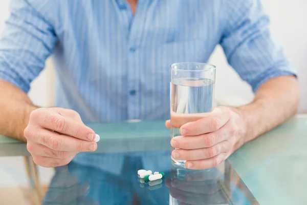 Casual businessman holding glass of water and tablet — Stock Photo, Image