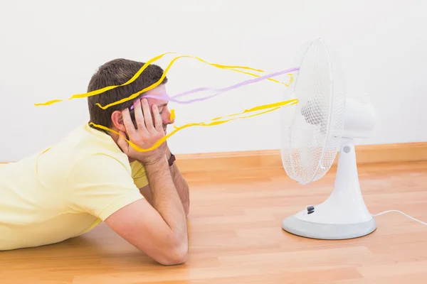 Hombre acostado en el suelo mirando ventilador en casa — Foto de Stock