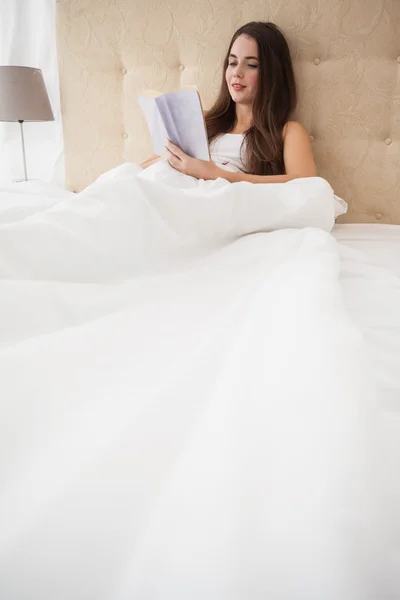 Bonita morena leyendo en la cama — Foto de Stock