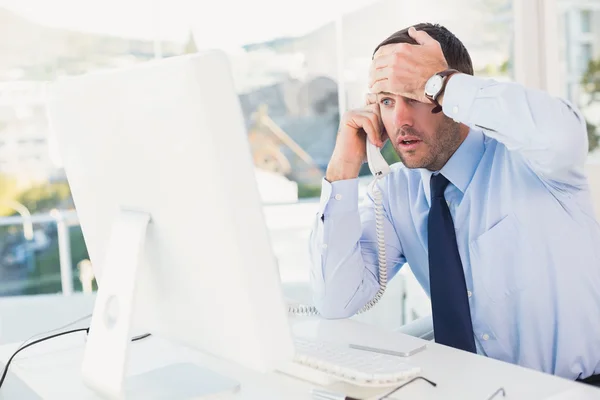 Empresario sorprendido en el teléfono en su escritorio — Foto de Stock