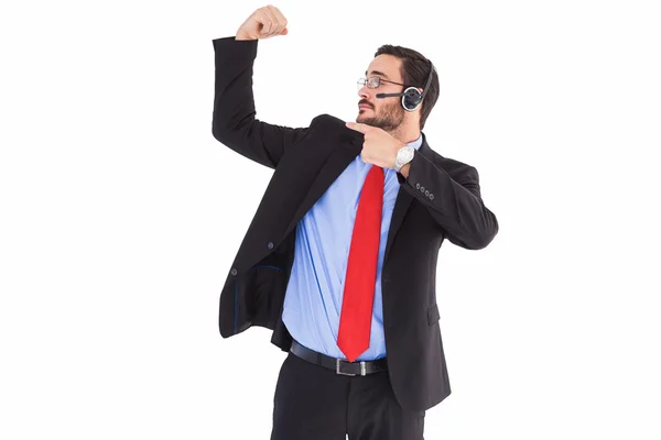 Hombre sonriente usando un auricular mientras señala su bíceps — Foto de Stock