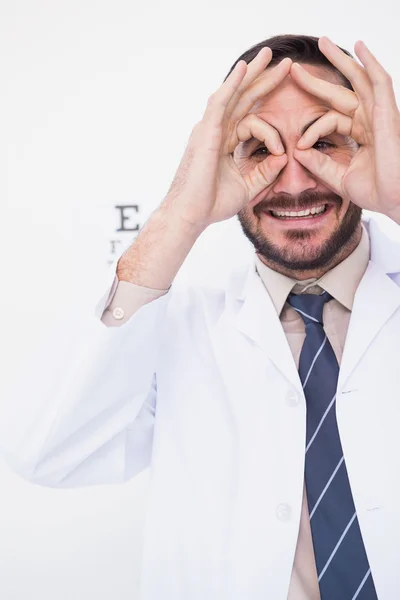 Smiling doctor forming eyeglasses with his hands — Stock Photo, Image