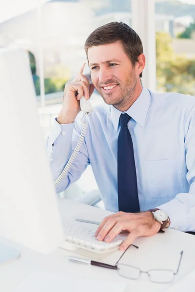 Homem de negócios sorrindo telefonando para sua mesa — Fotografia de Stock