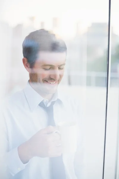 Sorridente empresário segurando caneca visto através da janela — Fotografia de Stock