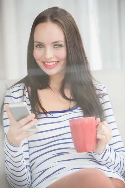 Söt brunett skicka text på soffan — Stockfoto