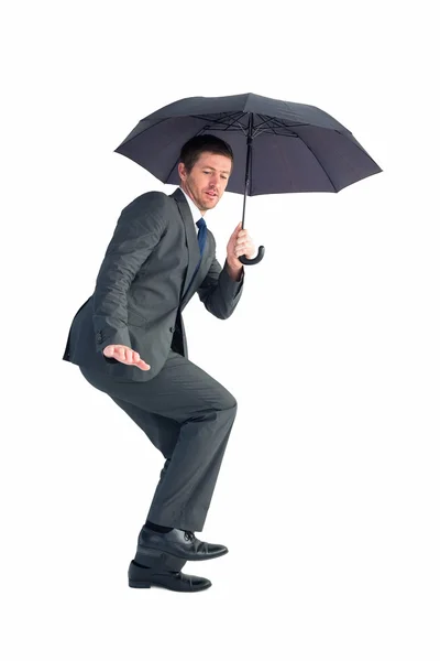 Empresário abrigando sob guarda-chuva preto — Fotografia de Stock