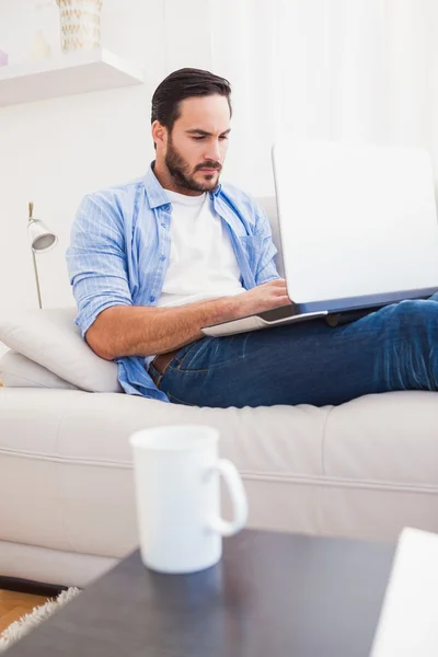 Homme couché sur le canapé en utilisant un ordinateur portable — Photo