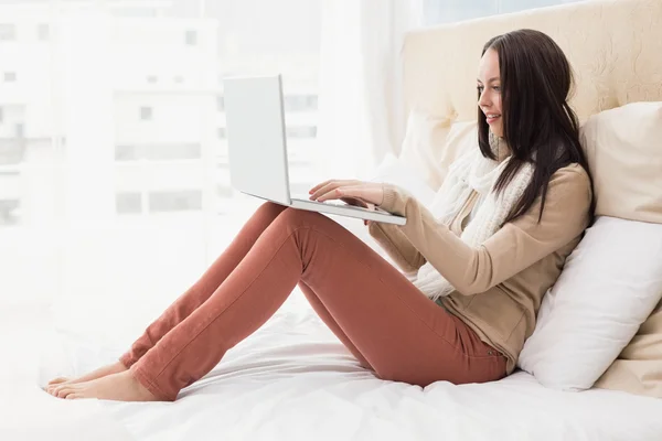 Bella bruna utilizzando il computer portatile sul letto — Foto Stock