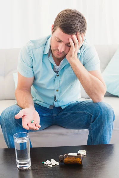 Hombre resaca con su medicina puesta en la mesa de café — Foto de Stock