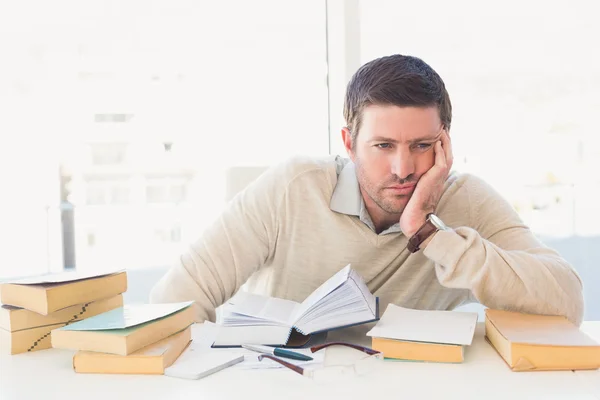 Empresário casual entediado estudando em sua mesa — Fotografia de Stock