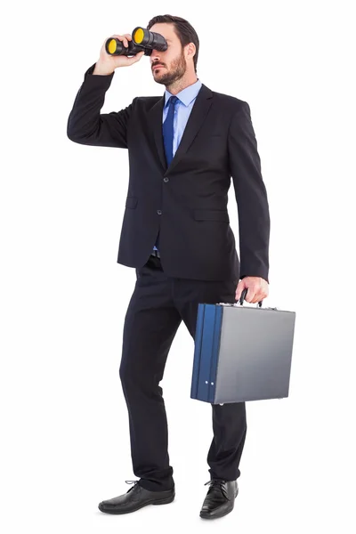 Businessman looking through binoculars holding briefcase — Stock Photo, Image