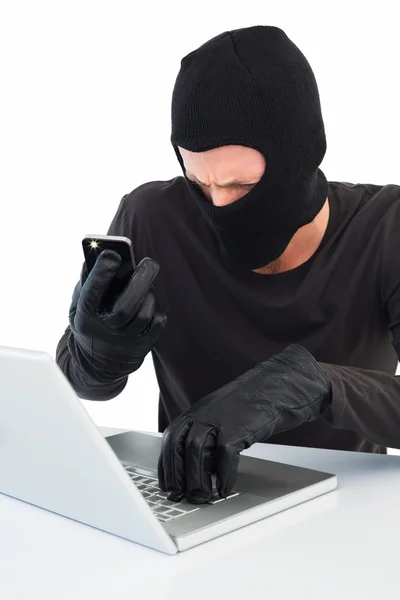 Hacker usando laptop e telefone — Fotografia de Stock
