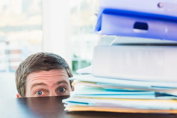 Scared businessman peeking over desk — Stock Photo, Image