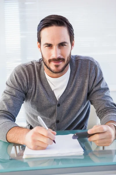 Homem casual feliz escrevendo em folhas pagando contas — Fotografia de Stock