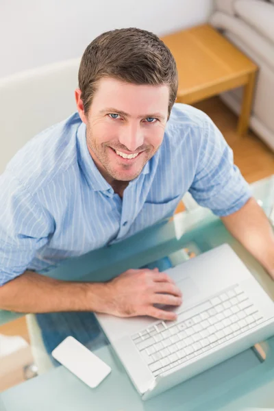 Улыбающийся бизнесмен, использующий ноутбук за столом — стоковое фото