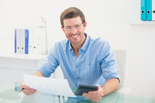 Empresário sorridente trabalhando em suas finanças em sua mesa — Fotografia de Stock