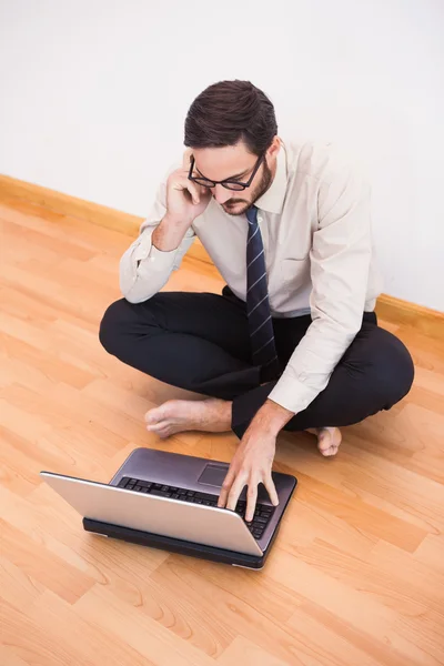 Geschäftsmann sitzt mit Handy und Laptop auf dem Boden — Stockfoto