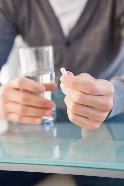 Partie médiane d'un homme tenant un verre d'eau et une pilule — Photo