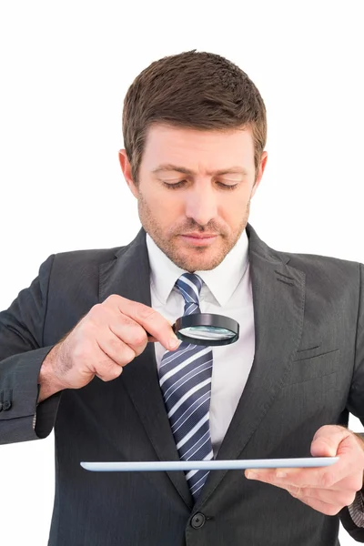 Empresário olhando para tablet com lupa — Fotografia de Stock