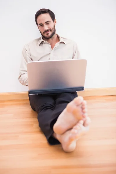 Avslappnad affärsman sitter på golvet medan du använder laptop — Stockfoto