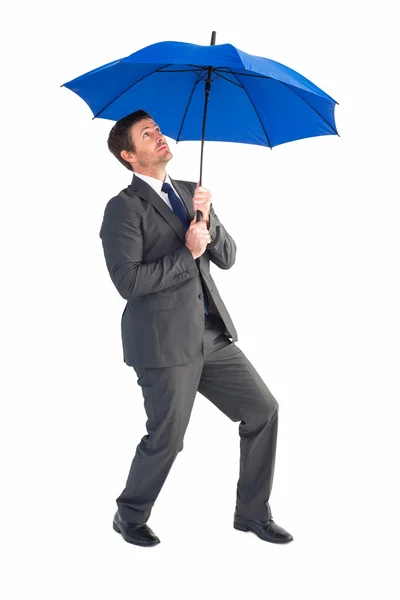 Empresario refugiándose bajo paraguas azul — Foto de Stock