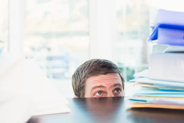 Φοβισμένος επιχειρηματίας peeking πάνω από την επιφάνεια εργασίας — Φωτογραφία Αρχείου