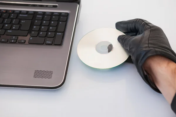 Burglar hacking and putting a cd-rom in laptop — Stock Photo, Image