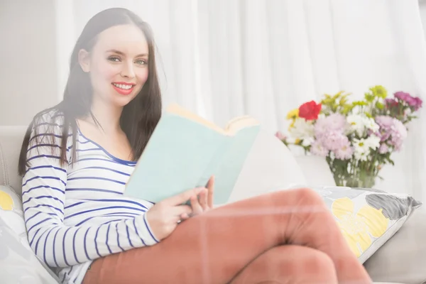 Hezká brunetka čtení knih na gauči — Stock fotografie