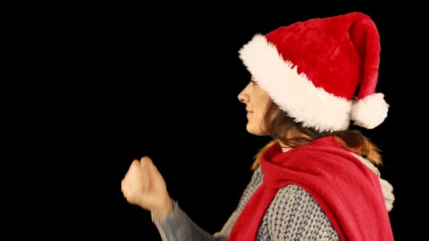 Девушка в шляпе Санты и теплая одежда дуют над руками — стоковое видео