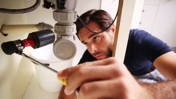Handsome plumber using screwdriver to fix sink — Stock Video